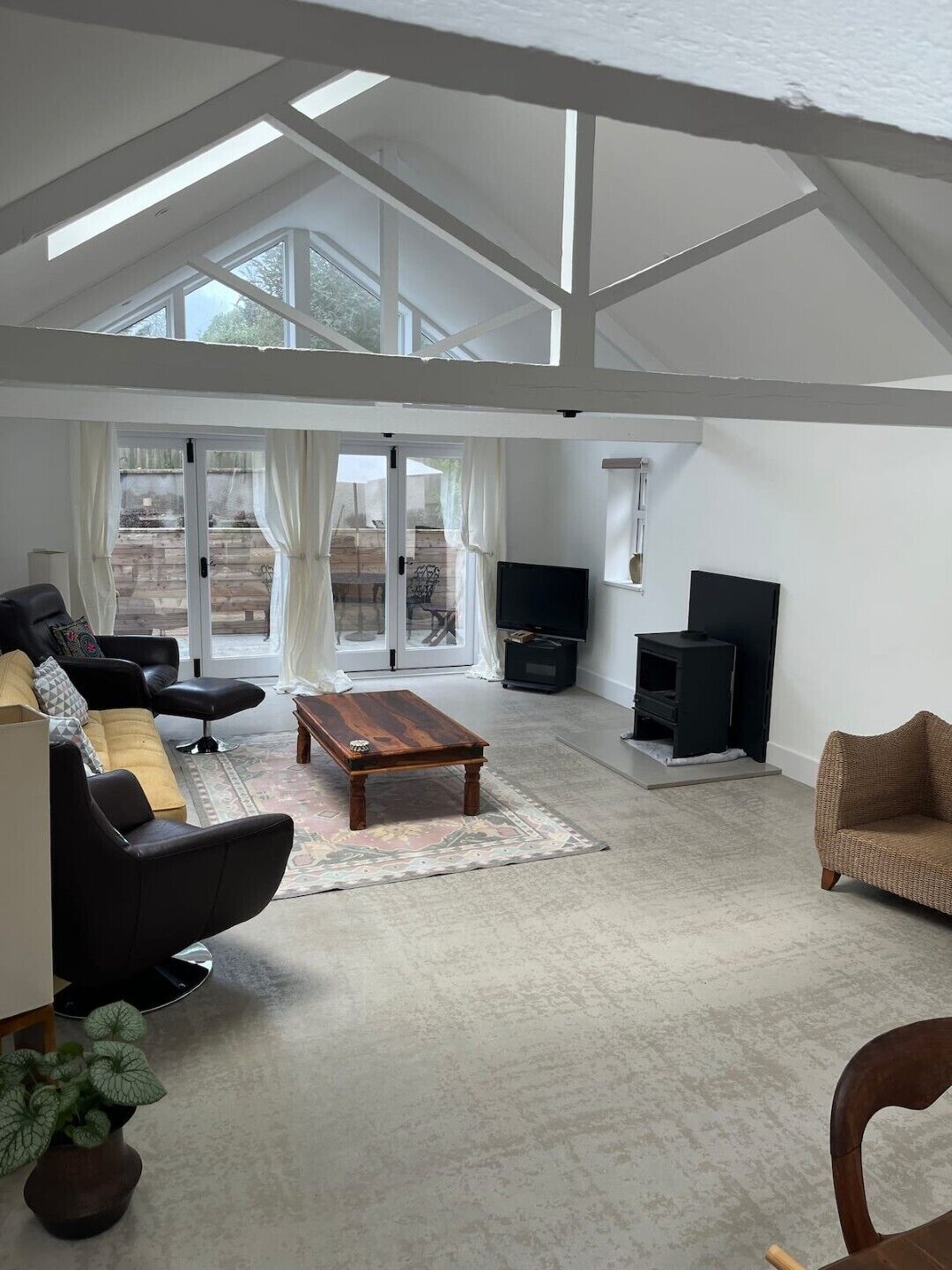 Un salon spacieux avec un haut plafond, une cheminée et une grande fenêtre.