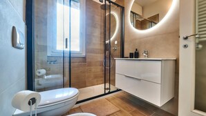Un bagno moderno con doccia vetrata, un water e un mobile lavabo con specchio.