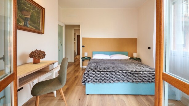 Una camera da letto con un letto, comodini, una scrivania, una sedia e una finestra.