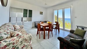 Une pièce comprenant une table à manger, des chaises, un canapé et un balcon avec vue.