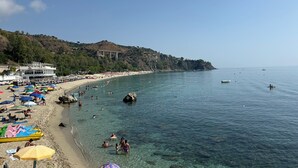 Une plage avec une eau claire, des parasols et des gens.
