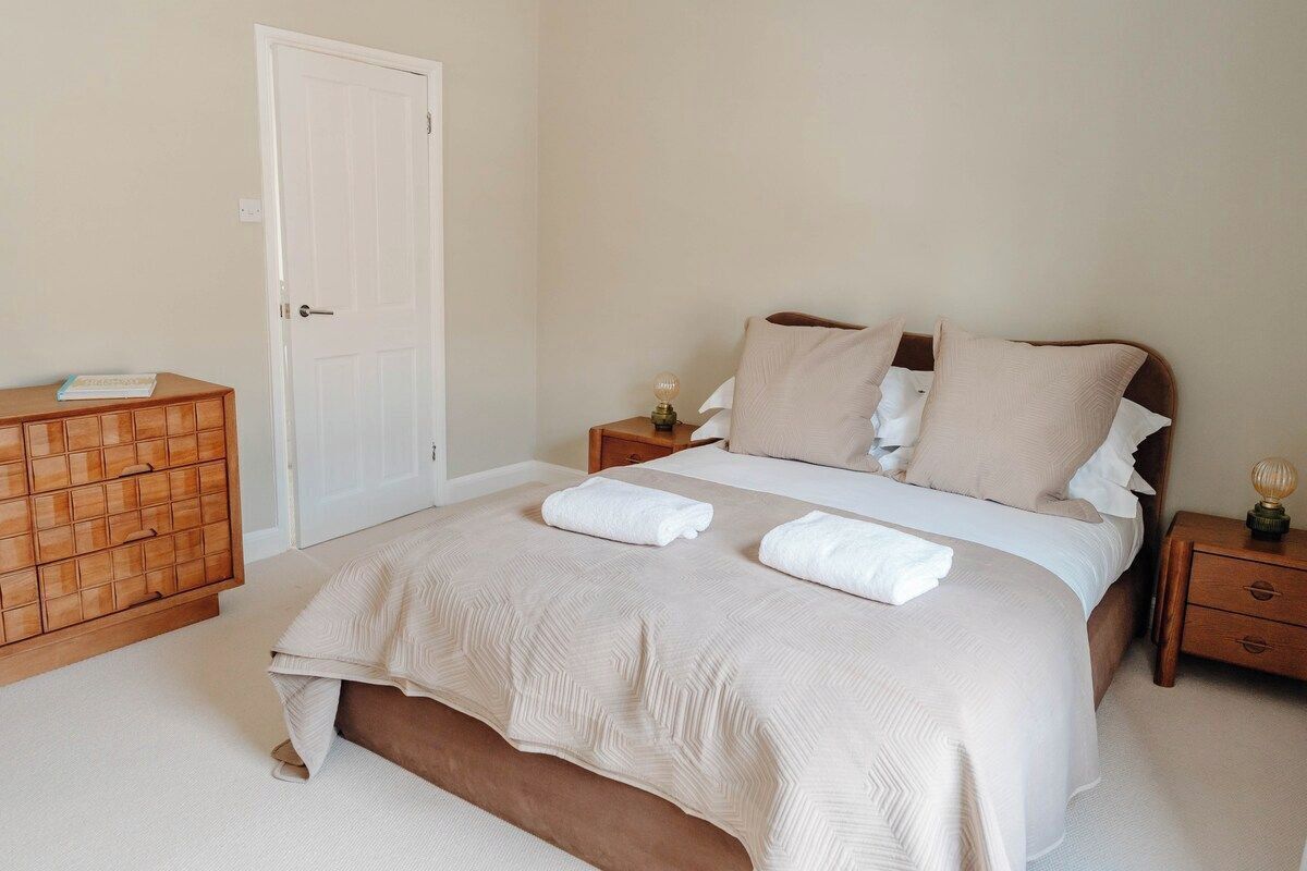 A bedroom with a bed, bedside tables, a dresser, and a door.
