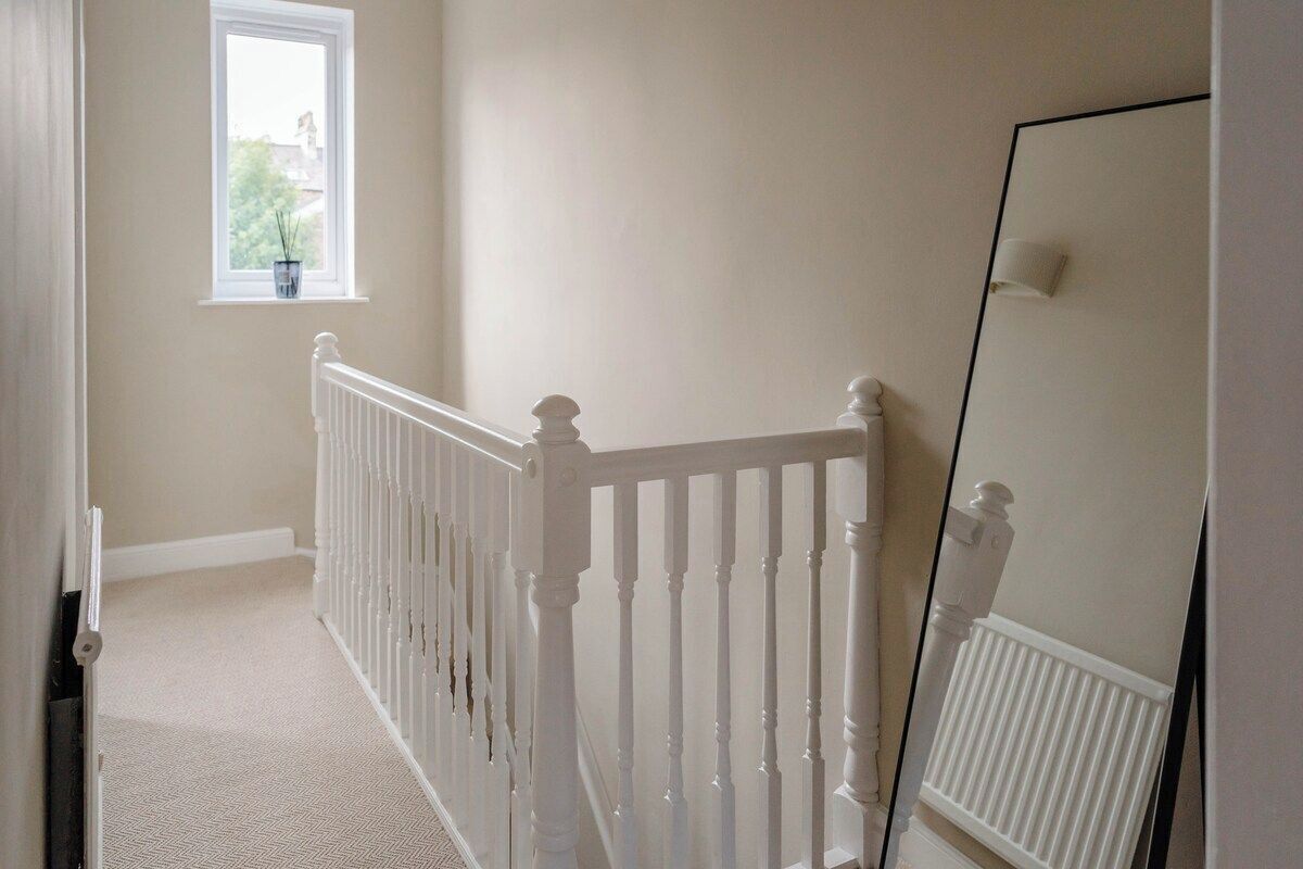 A staircase with white balusters, a window with a plant, and a radiator.