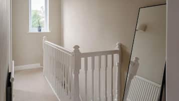A staircase with white balusters, a window with a plant, and a radiator.