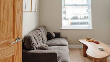 A room with a sofa, a wooden table, and a window with blinds.