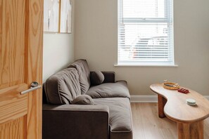 A room with a sofa, a wooden table, and a window with blinds. - Calming Boutique Design House - Walk to City (Clifton)
