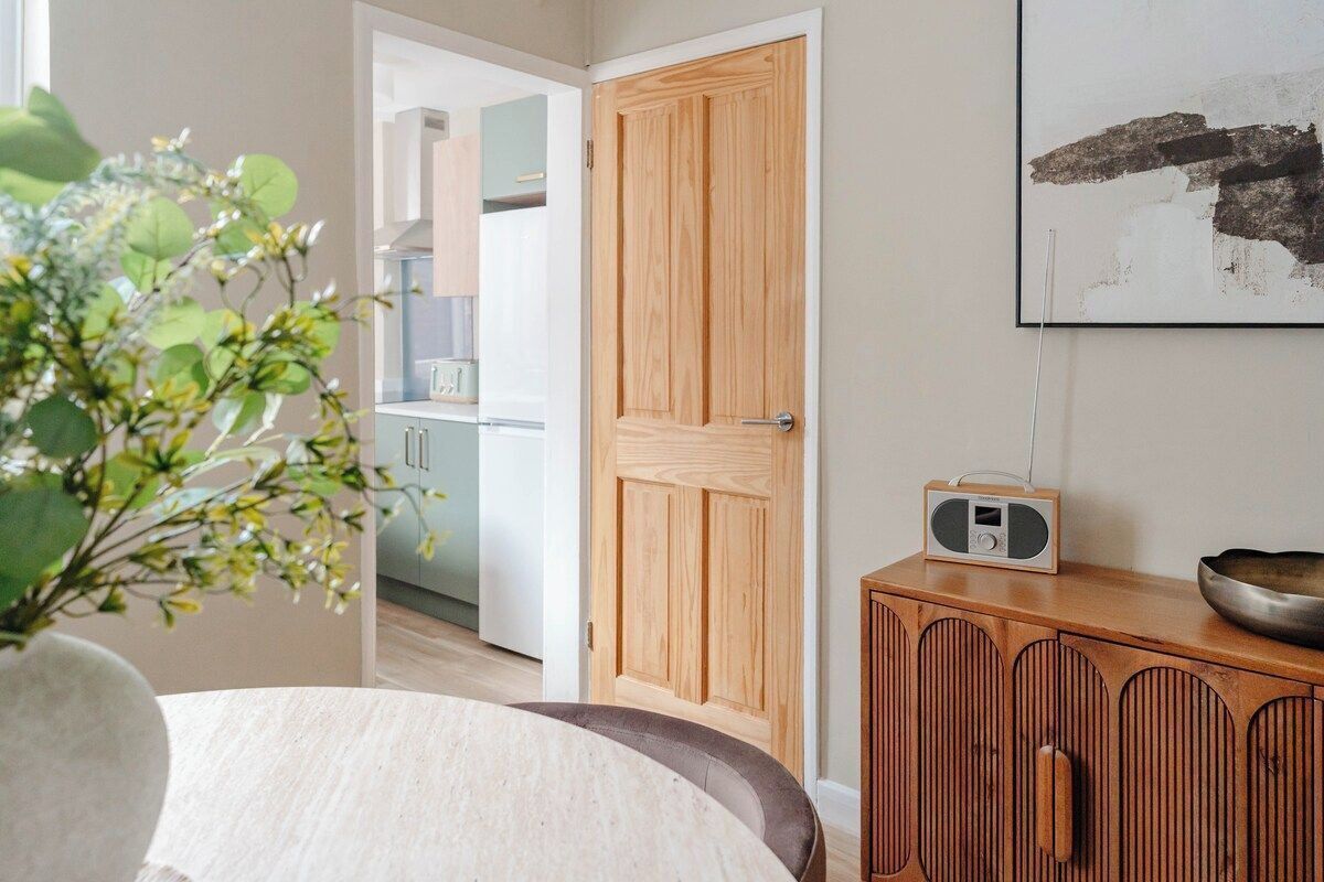 Ein Zimmer mit Holztür, einem Radio auf einem Schrank und einer Pflanze im Blumenvasen.