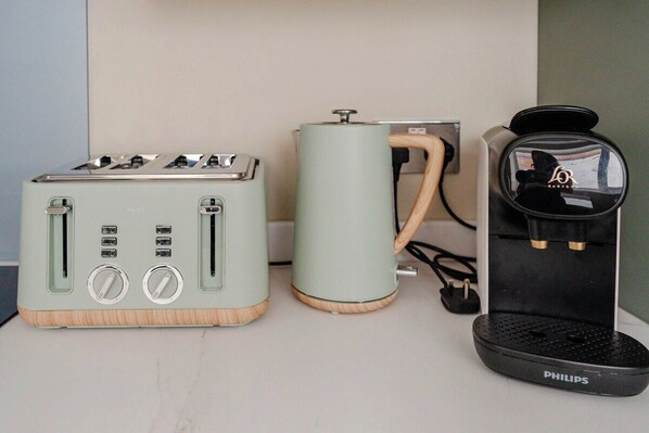 A kitchen area with a toaster, a coffee maker, and a kettle on a countertop.