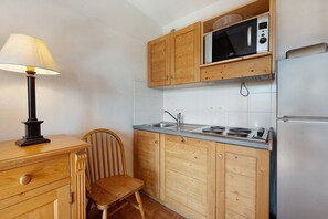 A kitchen with wooden cabinets, a microwave, a stove, and a refrigerator.