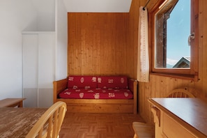 A wooden cabin interior with a sofa, a table, and a window with a view.
