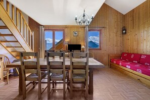 En interiör med träinredning, bestående av ett matbord, stolar, en soffa och en trappa.