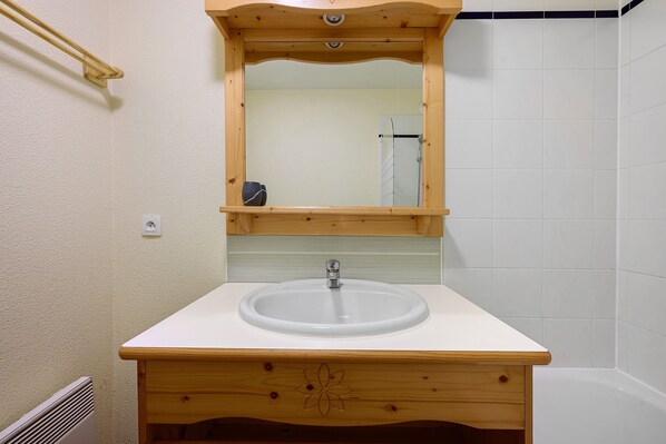 A bathroom with a wooden vanity, a sink, and a mirror.