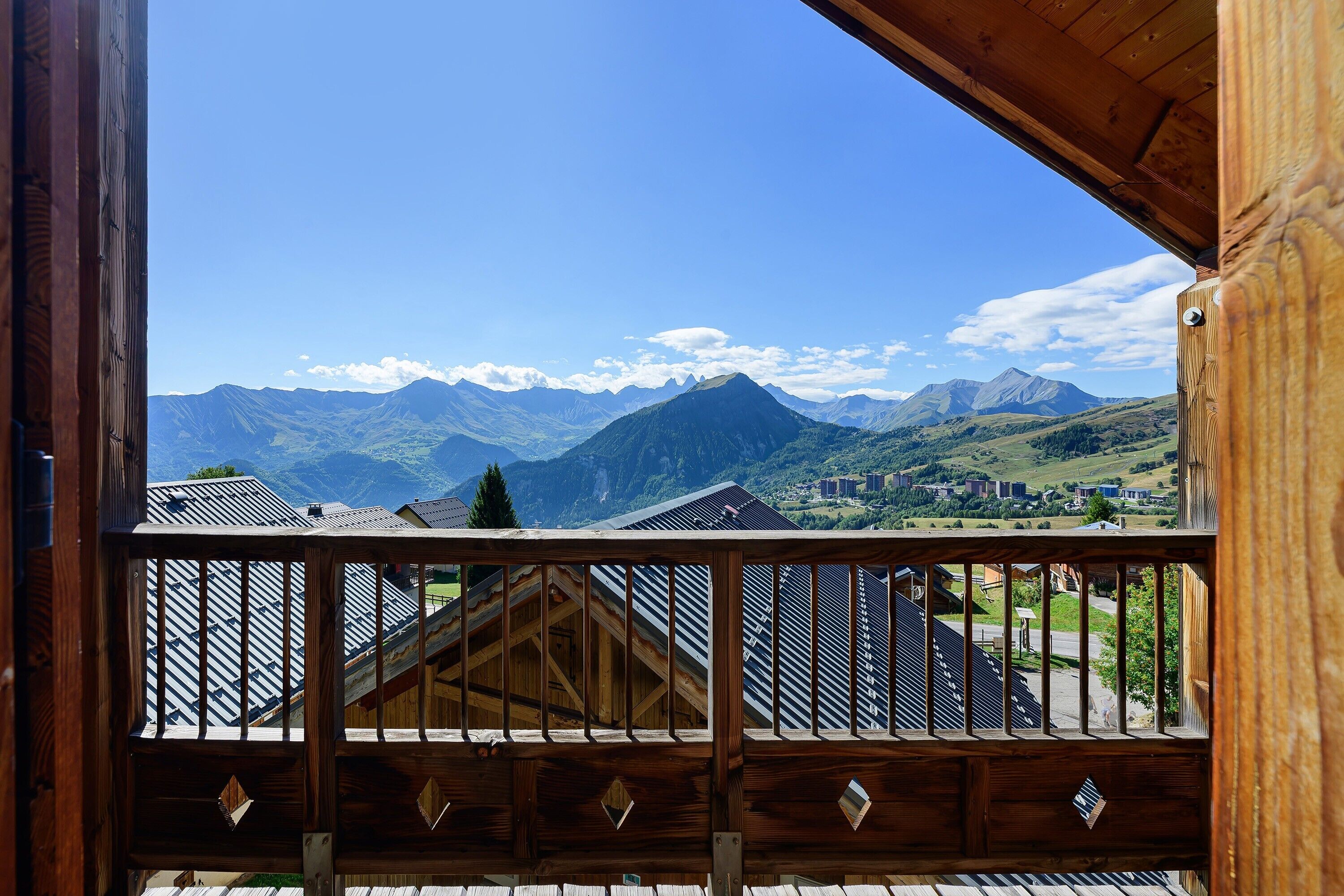 A wooden balcony with a view of mountains and a town.