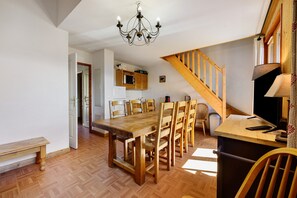 Ein Essbereich mit einem Holztisch und Stühlen, einer Chandelieber und einer Treppe.