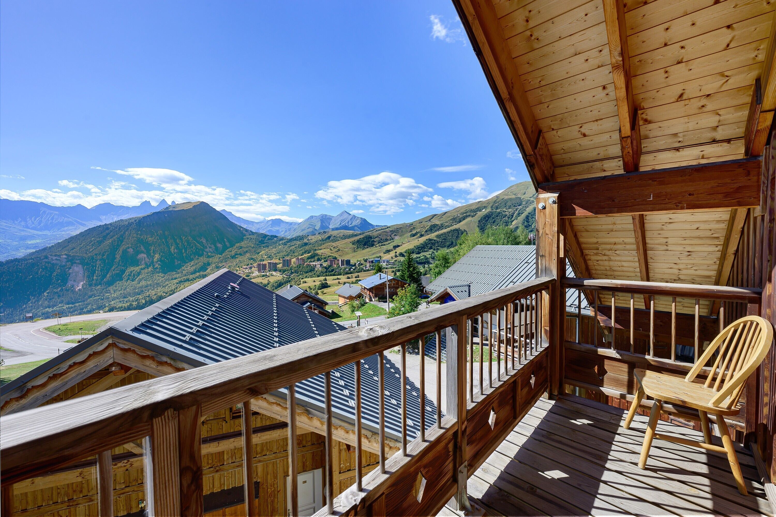 A wooden balcony with a view of mountains and a valley.
