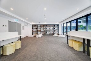 Eine moderne Bibliothek mit weißen Wänden, Teppichboden und einem großen Bücherregal.
