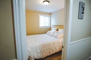 A bedroom with a bed, a window, and a wall-mounted electrical panel.