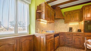 Una cucina con mobili in legno, lavastoviglie, lavello e una finestra con tende.