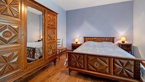 Una camera da letto con un letto di legno, uno specchio grande, due comodini e un tavolino da notte.