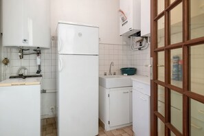 Een kleine keuken met een koelkast, wastafel en kastjes.