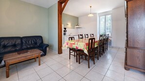 Een woonkamer met een bank, een salontafel, en een eethoek met een tafel en stoelen.