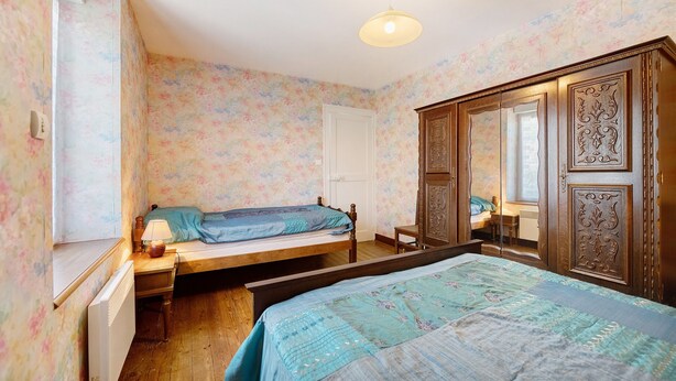 Een slaapkamer met een bed, een dressoir, een spiegel en een raam.