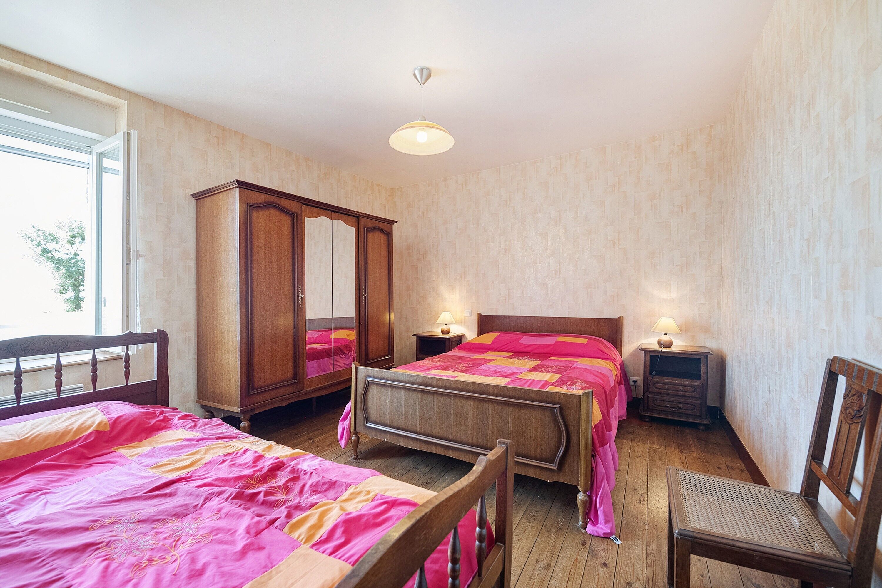 Une chambre avec deux lits, une armoire, une chaise et des lampes de chevet.
