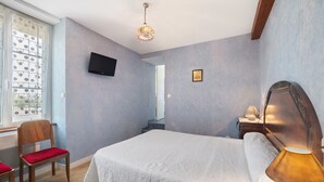 A bedroom with a bed, a chair, a TV, a lamp, and a window with curtains. - Guest Room "Chambre 1" with Wi-Fi (Courtils)