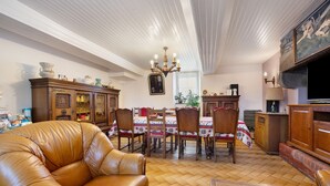 A dining area with a wooden table and chairs, a chandelier, and a leather sofa. - Guest Room "Chambre 1" with Wi-Fi (Courtils)