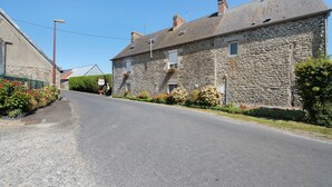 Une rue étroite bordée de bâtiments en pierre, dont certains présentent des cheminées et des fenêtres apparentes.