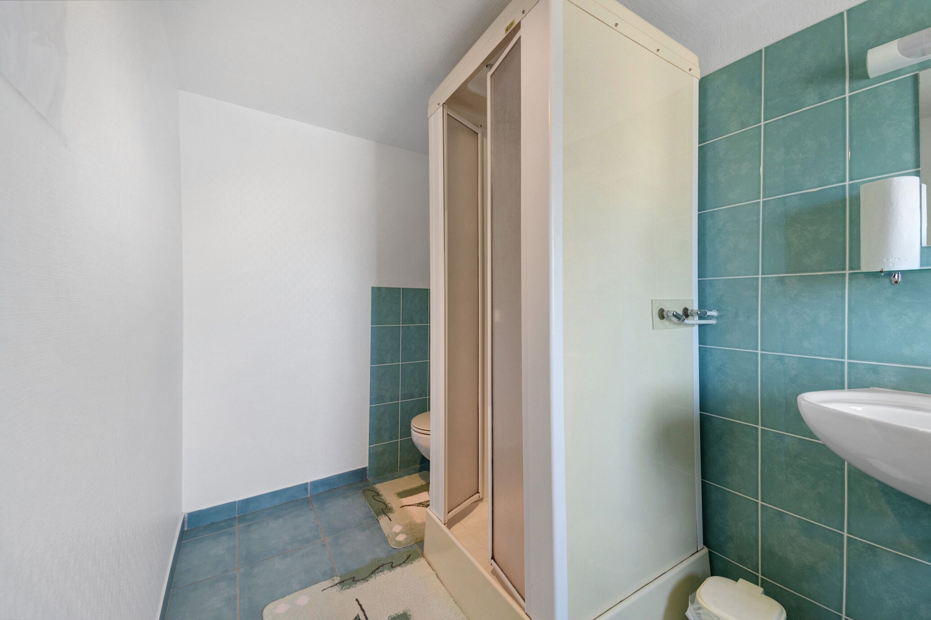 Un baño con inodoro, lavamanos y zona de ducha.