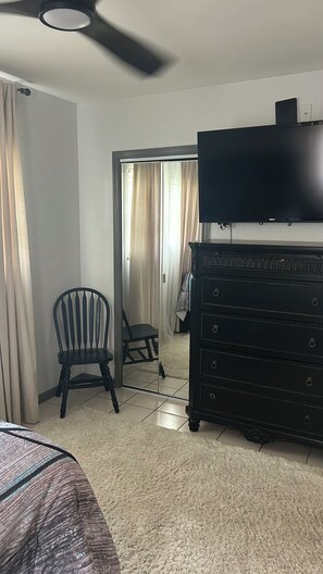 Ein Hotelzimmer mit Bett, Kommode, Sessel und Fernseher.