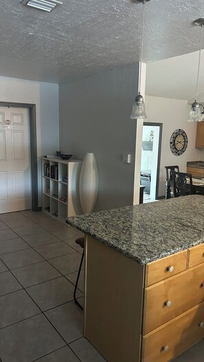 A kitchen with a granite countertop, wooden cabinets, and a tiled floor. - Charming 2-bedroom house with AC in sunny Orlando (Orlando)