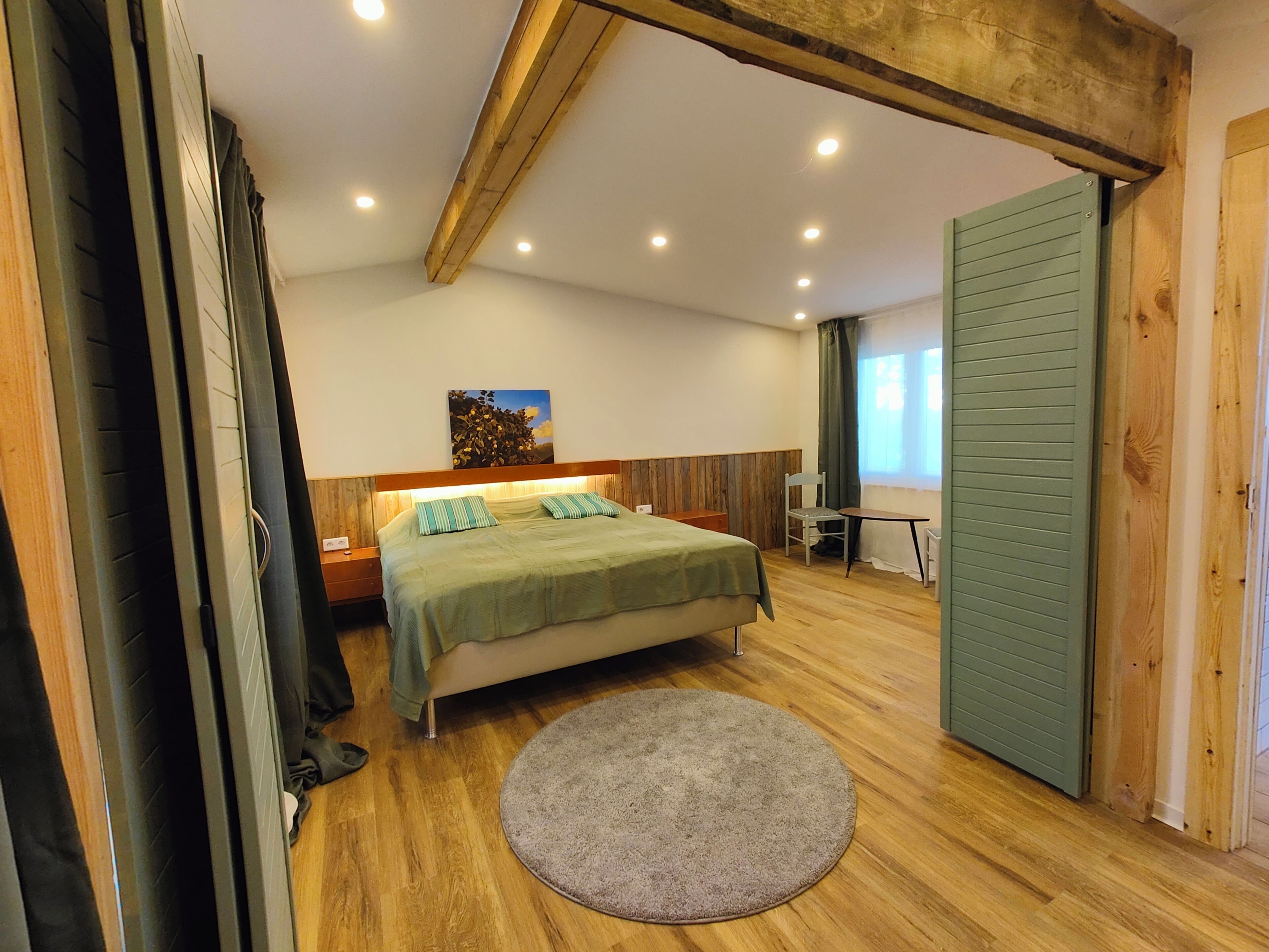 A bedroom with a bed, a desk, a chair, and a round rug.