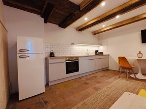 A modern kitchen with white cabinetry, a built-in oven, and a wooden ceiling. - alte Wiesenresidenz (Saal)
