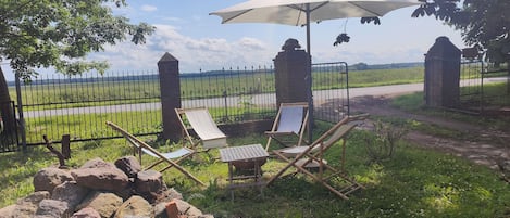 A tranquil outdoor seating area with a view of a vineyard, a stone wall, and a metal fence.