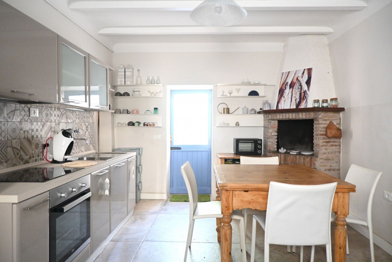 A modern kitchen with a dining area, featuring a built-in oven, microwave, and a brick fireplace.