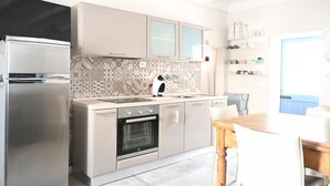 A modern kitchen with a built-in oven, a refrigerator, and a dining area with a wooden table and chairs. - SE306 - Senigallia, four-room apartment on two levels near the sea and the historic center. (Senigallia)