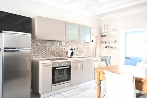 Eine moderne Küche mit Einbauofen, Kühlschrank und Essbereich mit Holztisch und Stühlen.