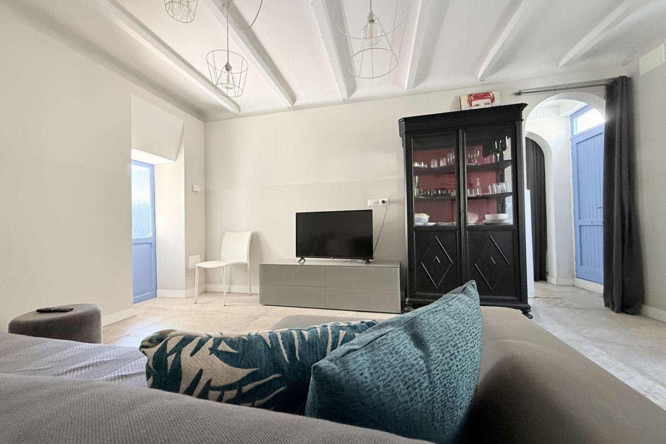 A modern living room with a sofa, a flat-screen TV, a cabinet, and a chair.