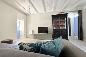 Ein modernes Wohnzimmer mit einer Couch, einem Flachbildfernseher, einem Schrank und einem Sessel.