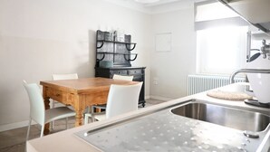 A kitchen with a wooden table, white chairs, a black cabinet, and a window. - SE306 - Senigallia, four-room apartment on two levels near the sea and the historic center. (Senigallia)