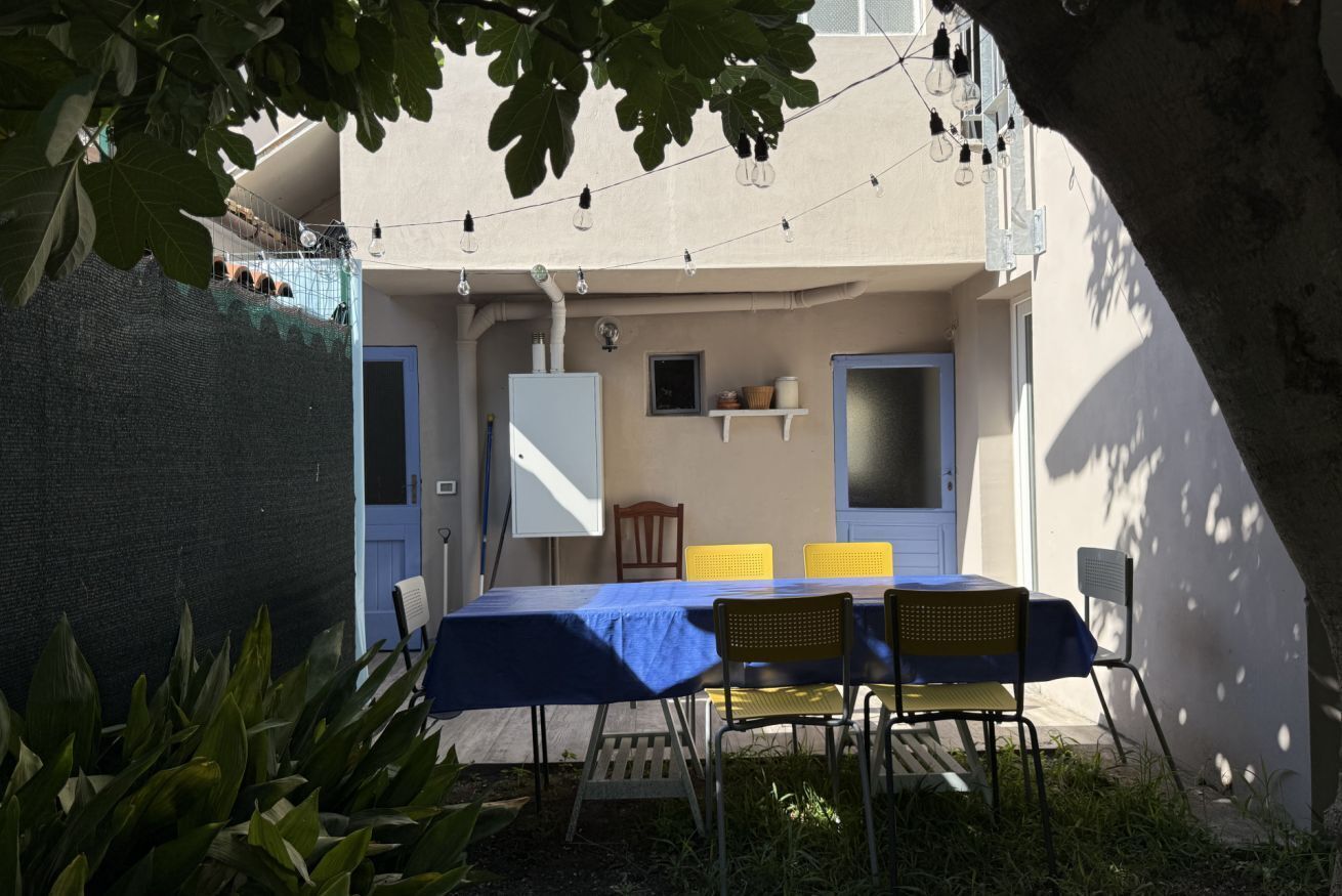 Un espace de restauration en plein air avec une table et des chaises, une nappe bleue et des guirlandes lumineuses.
