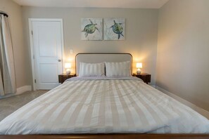 A bedroom with a bed, two bedside lamps, a door, and two wall art pieces. - Modern 2BR Near Downtown Ipswich (Ipswich)