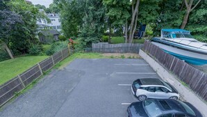 Un'area di parcheggio con due automobili, circondata da una recinzione in legno e vegetazione.