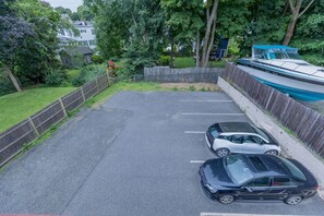 Un área de estacionamiento con dos autos, rodeada por una cerca de madera y follaje.