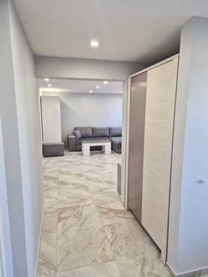 A hallway with a marble floor, a grey sofa set, a small white coffee table, and a wardrobe. - Complete Luxury Home (Chalon-sur-Saône)