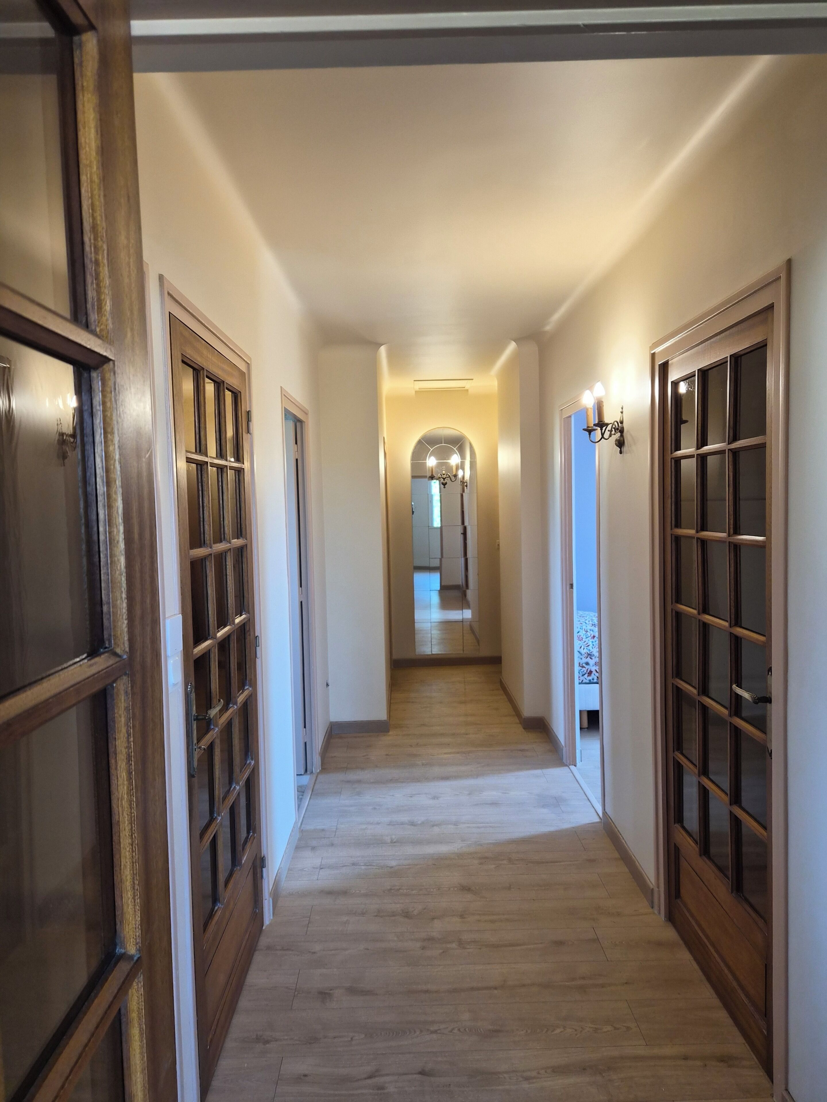 Un couloir avec des portes en bois et un lustre.