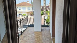 A covered balcony with a tiled floor, a hanging light fixture, and a view of neighboring buildings. - Entire Luxury Home (Chalon-sur-Saône)