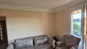 A living room with a sofa and armchair, wooden flooring, and a ceiling light fixture. - Entire Luxury Home (Chalon-sur-Saône)